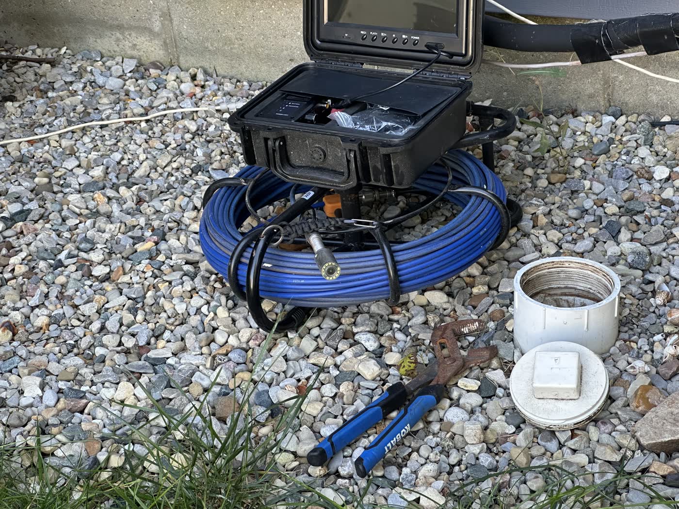 Sewer scope camera, monitor and cable reel staged at a residential cleanout.
