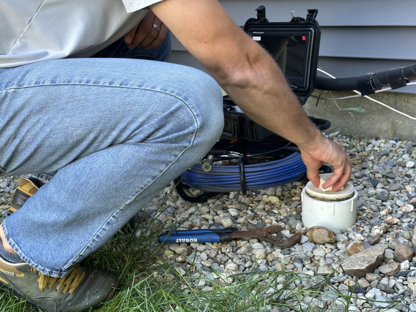 Inspector opening a yard cleanout cap at the start of a residential sewer scope.