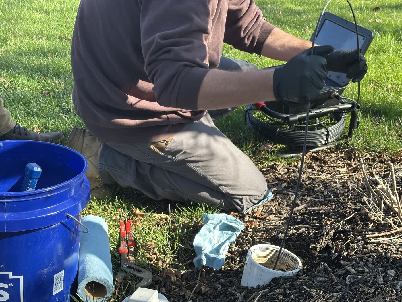 Inspector reviewing the live sewer camera monitor during a yard inspection.